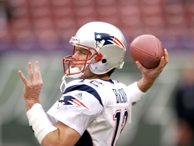 Tom Brady throwing a football in a New England Patriots jersey
